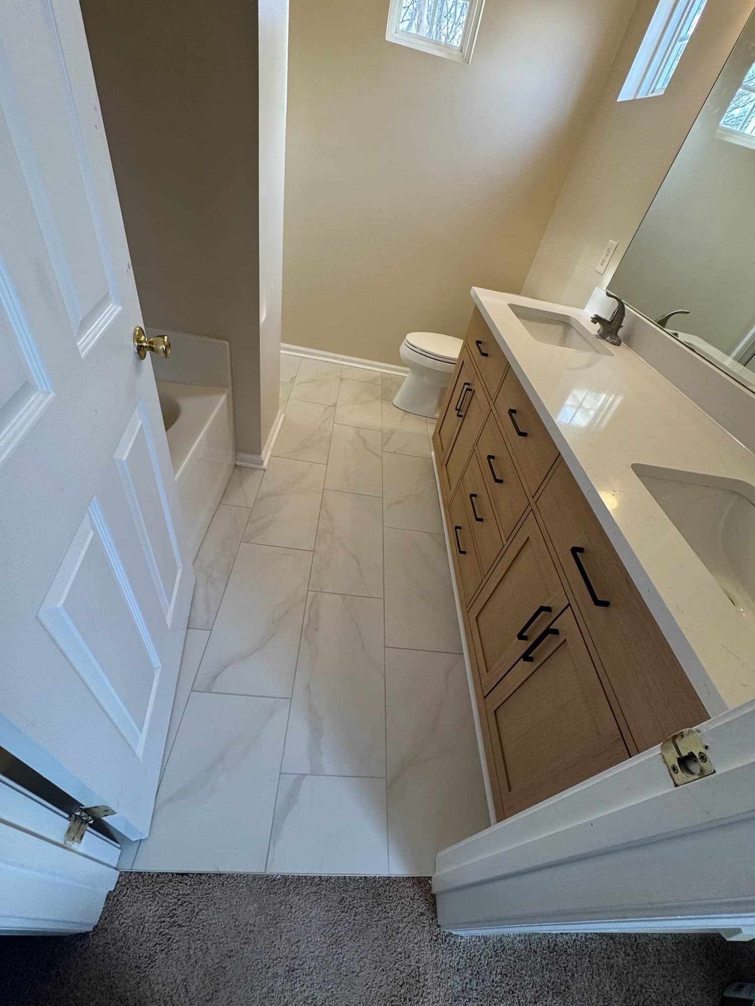 Bathroom remodel with oak shaker double vanity and marble-look porcelain floor in Charlotte NC
