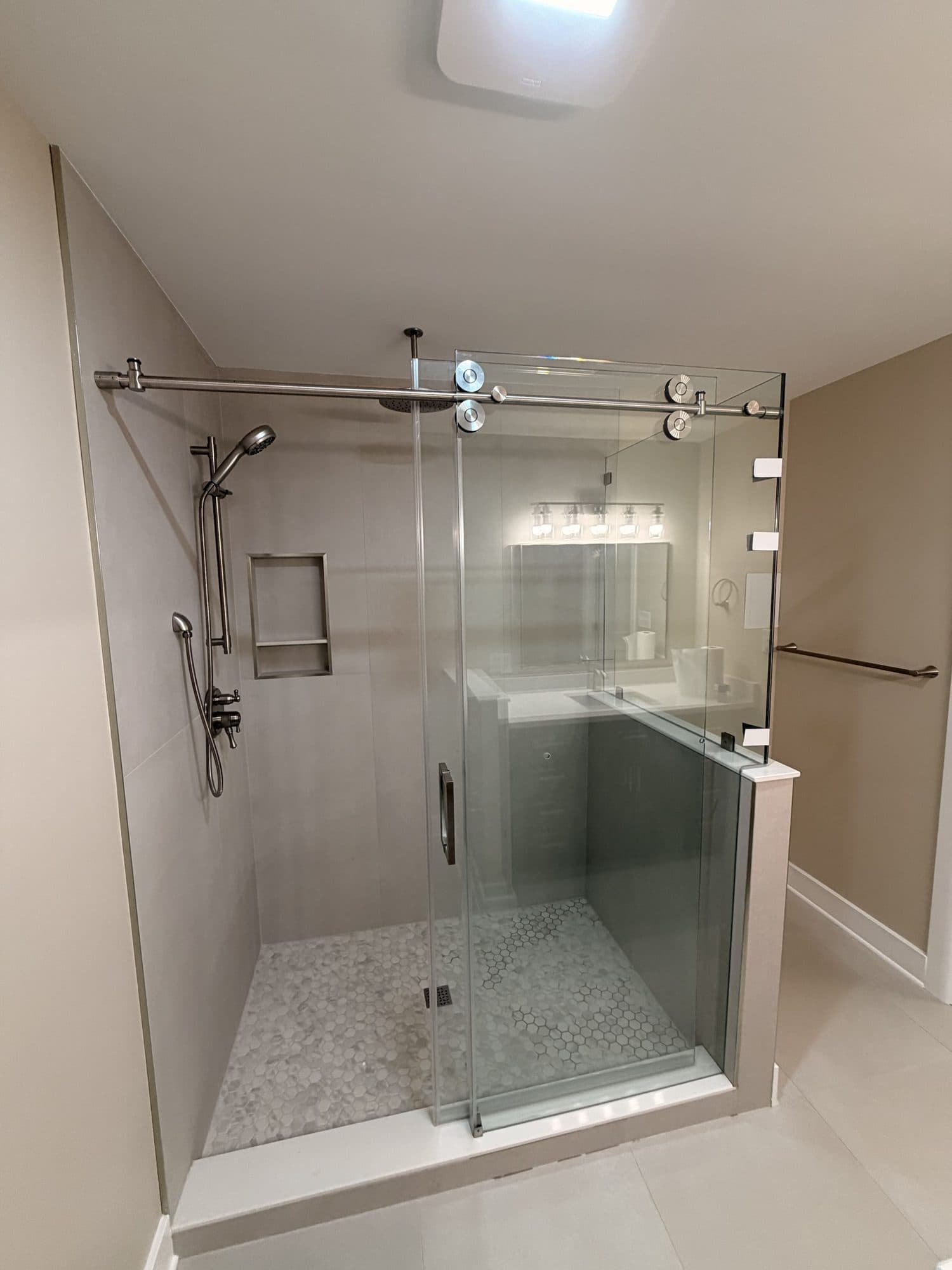 Walk-in shower with sliding glass door and hex mosaic floor in a Charlotte NC bathroom remodel