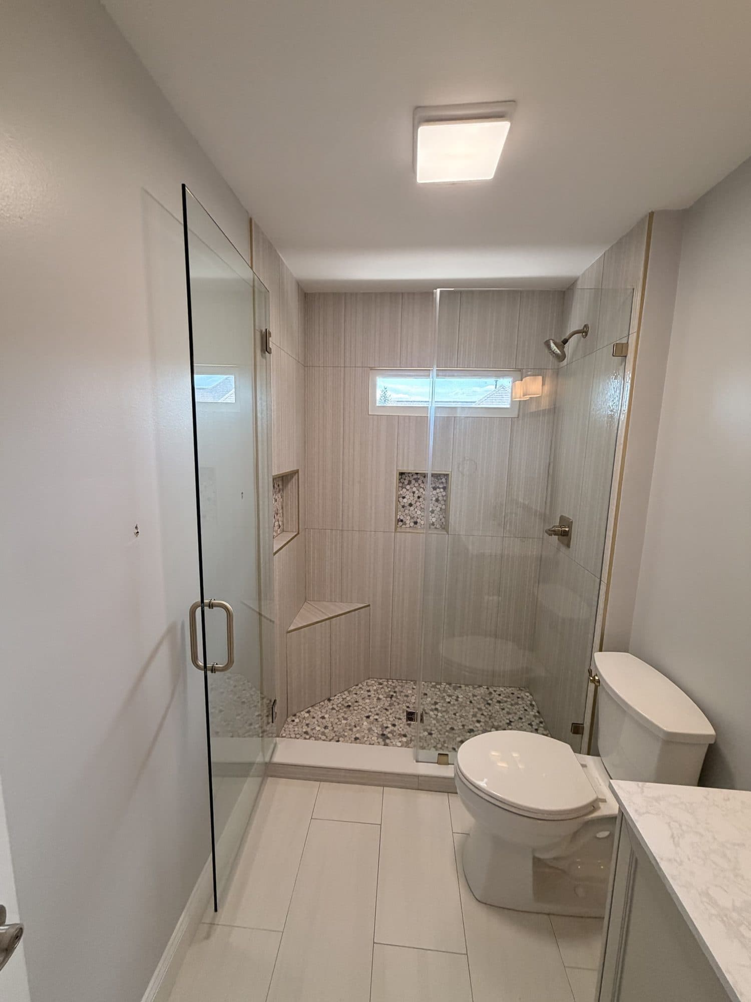 Walk-in shower with frameless glass door, niche and mosaic floor in a Charlotte NC bathroom remodel