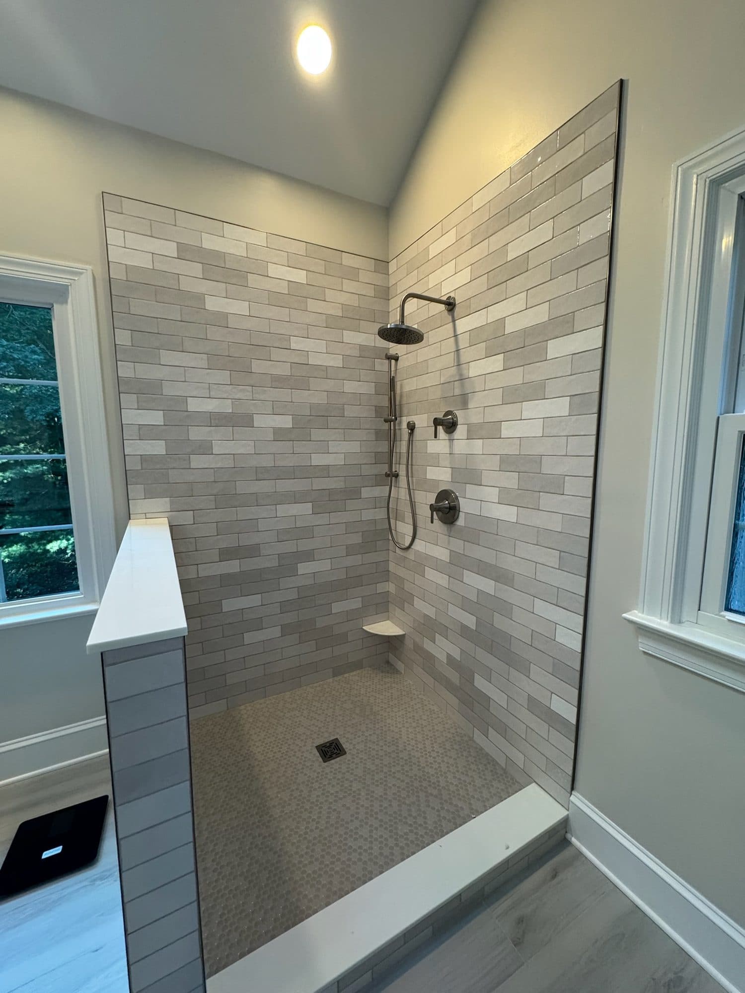 Gray handmade-look subway tile walk-in shower with half wall and mosaic floor in Charlotte NC