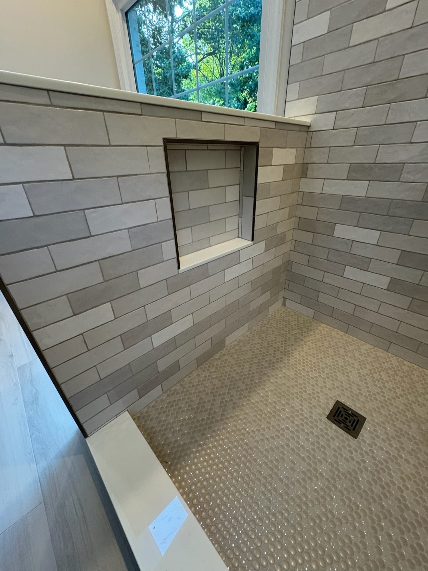 Penny-round mosaic shower floor and recessed niche lined up with the tile pattern, Charlotte NC