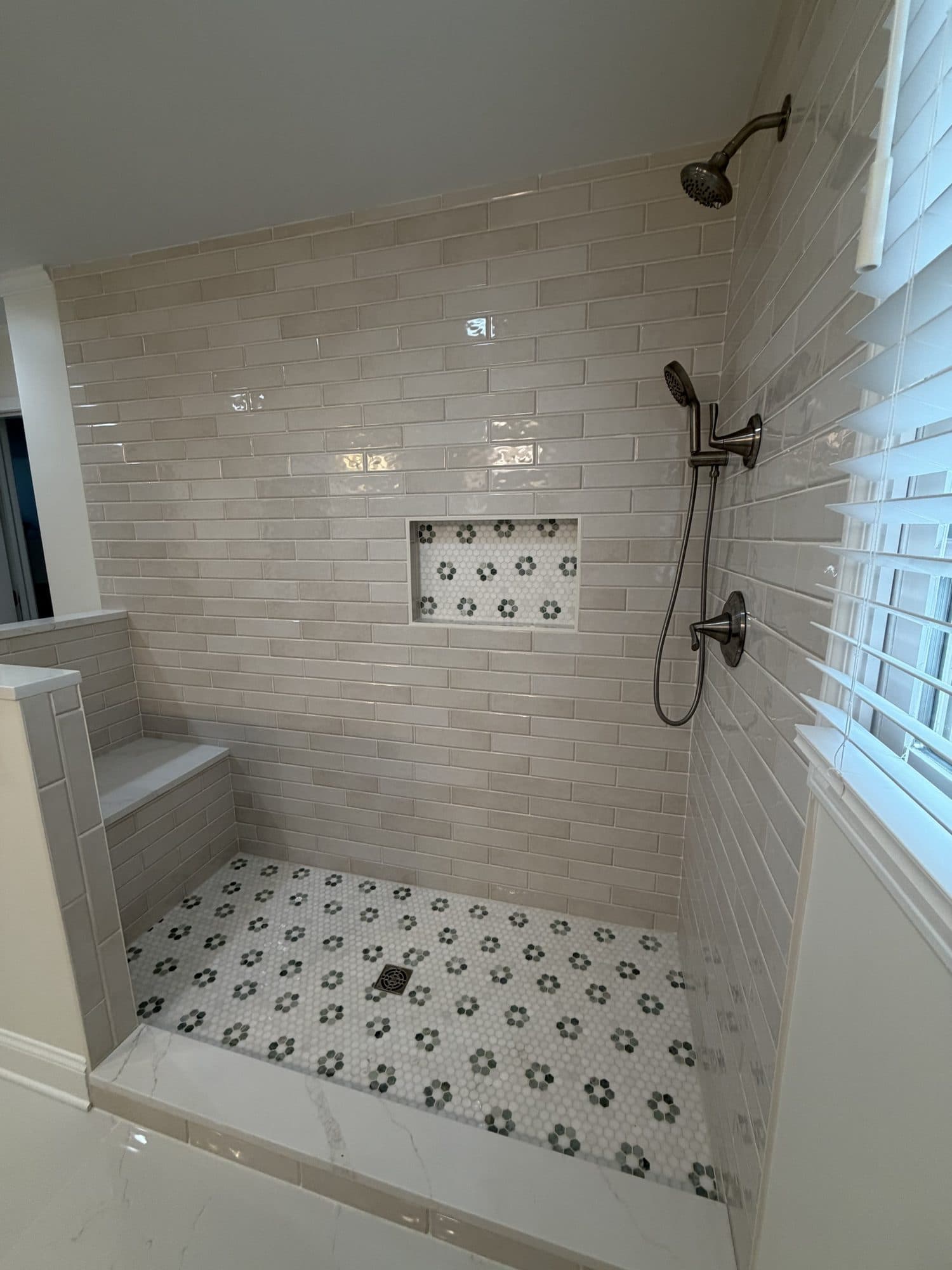 Beige handmade-look subway tile shower with flower hex mosaic floor, niche and built-in bench in Charlotte NC