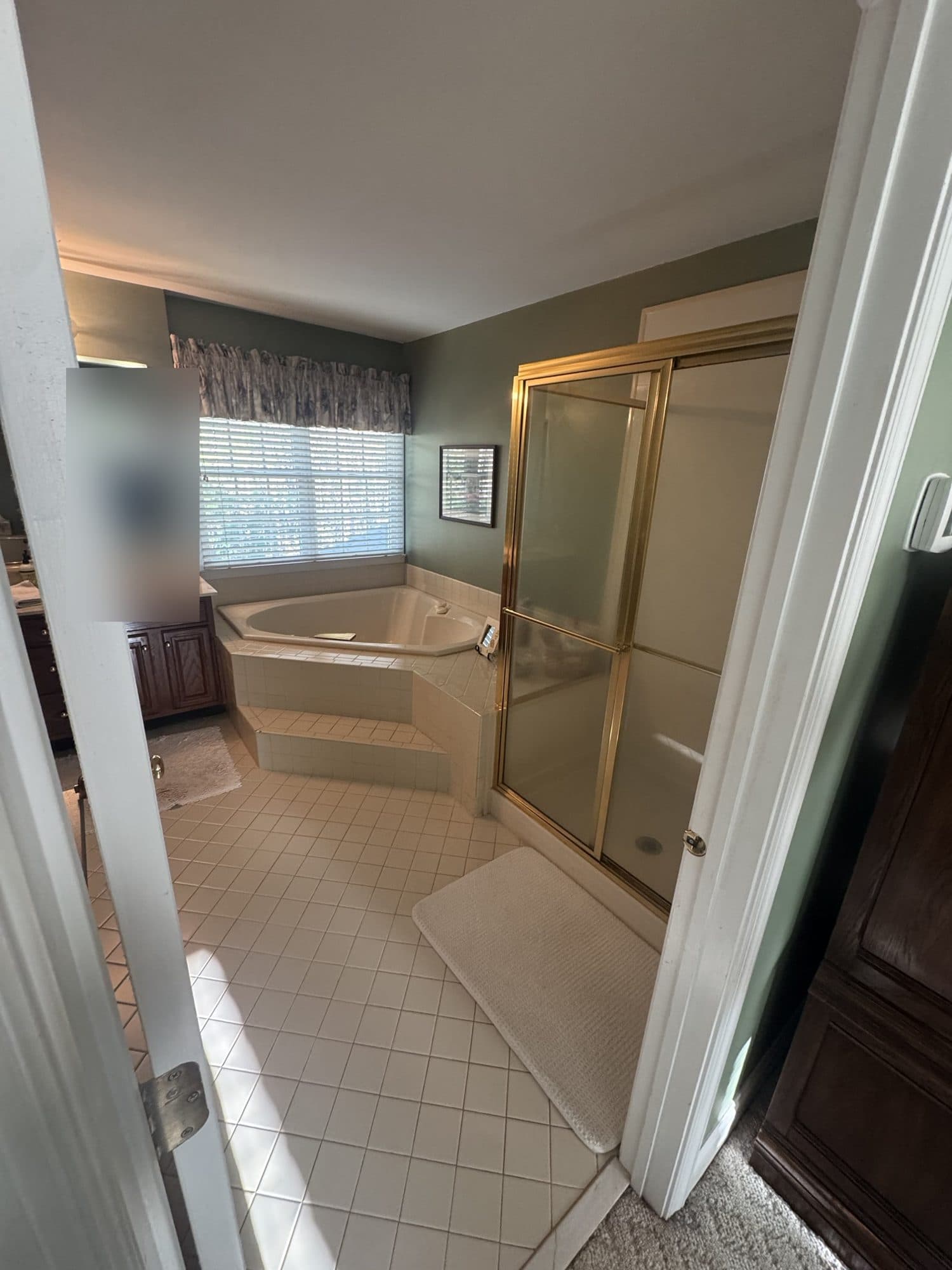 Before: gold-framed shower door and dated tile floor in a Matthews, NC primary bathroom