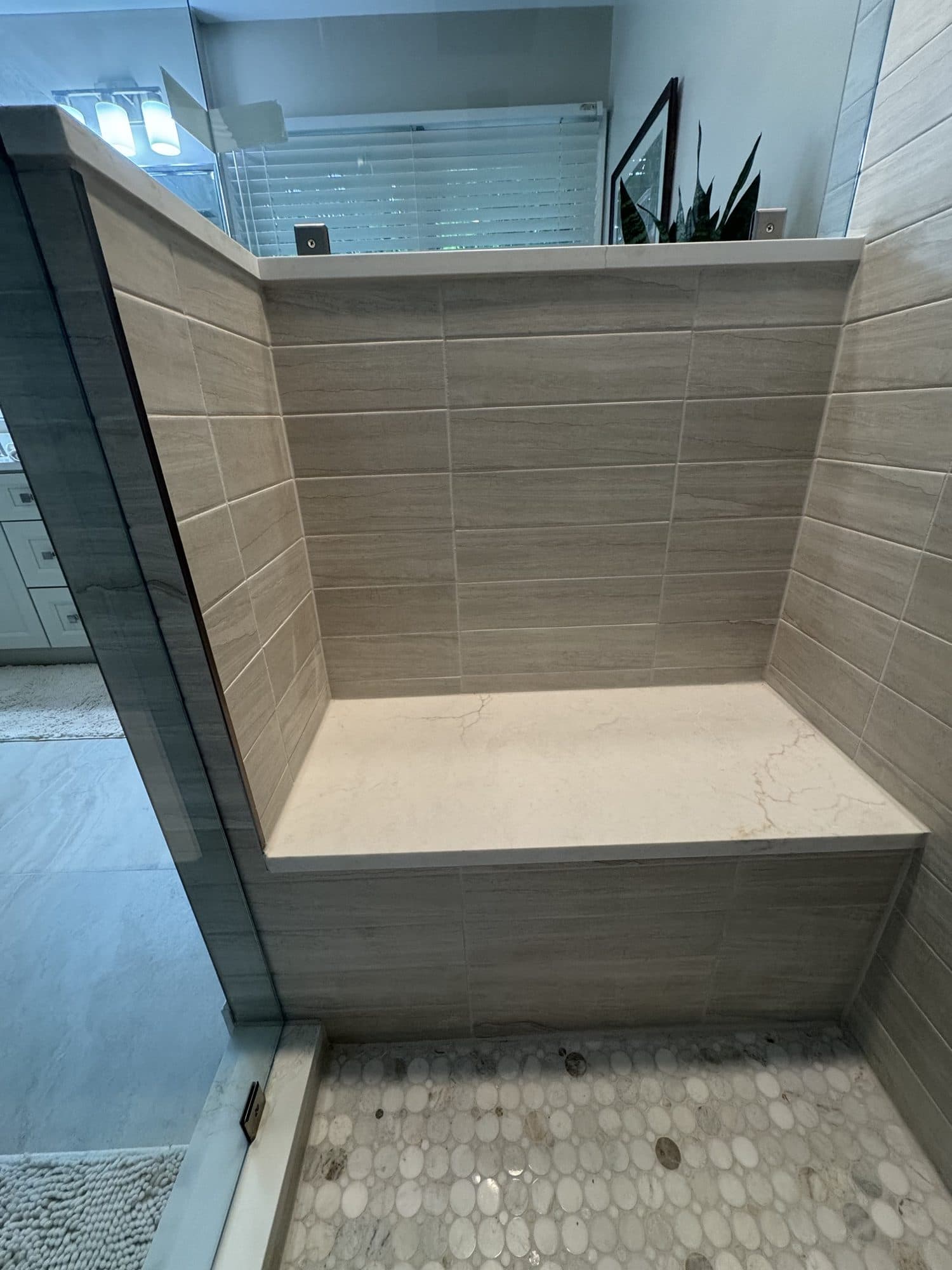 Built-in quartz shower bench and porcelain wall tile in a Matthews, NC bathroom remodel
