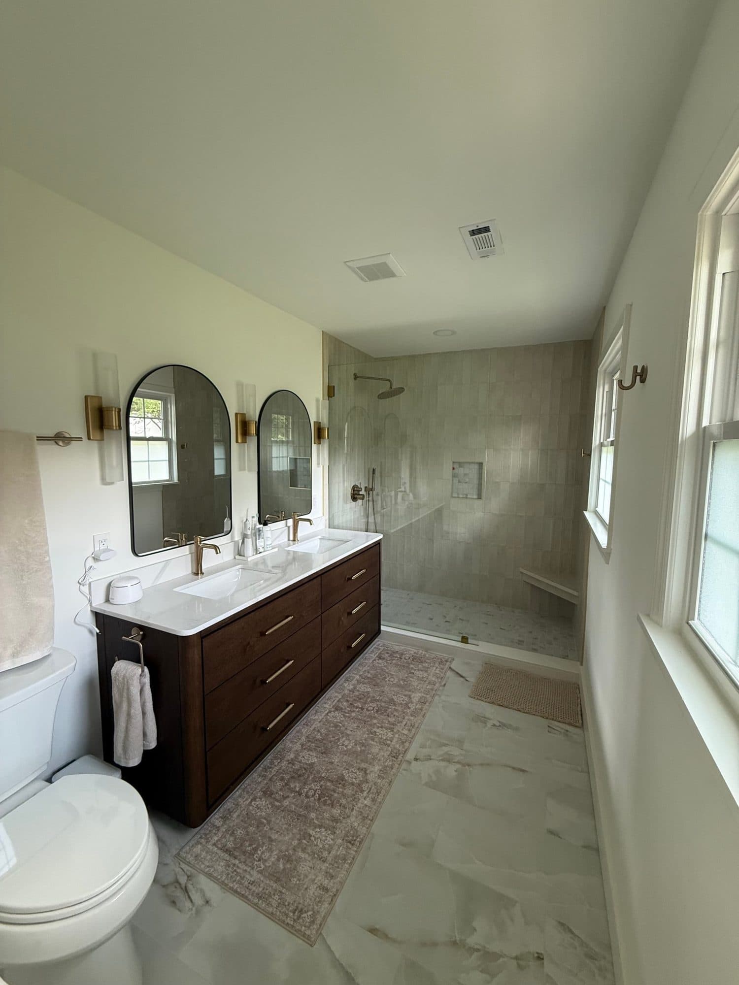 Primary bathroom remodel in a 1960s SouthPark, Charlotte home: walk-in shower, dark wood double vanity and marble-look porcelain floor