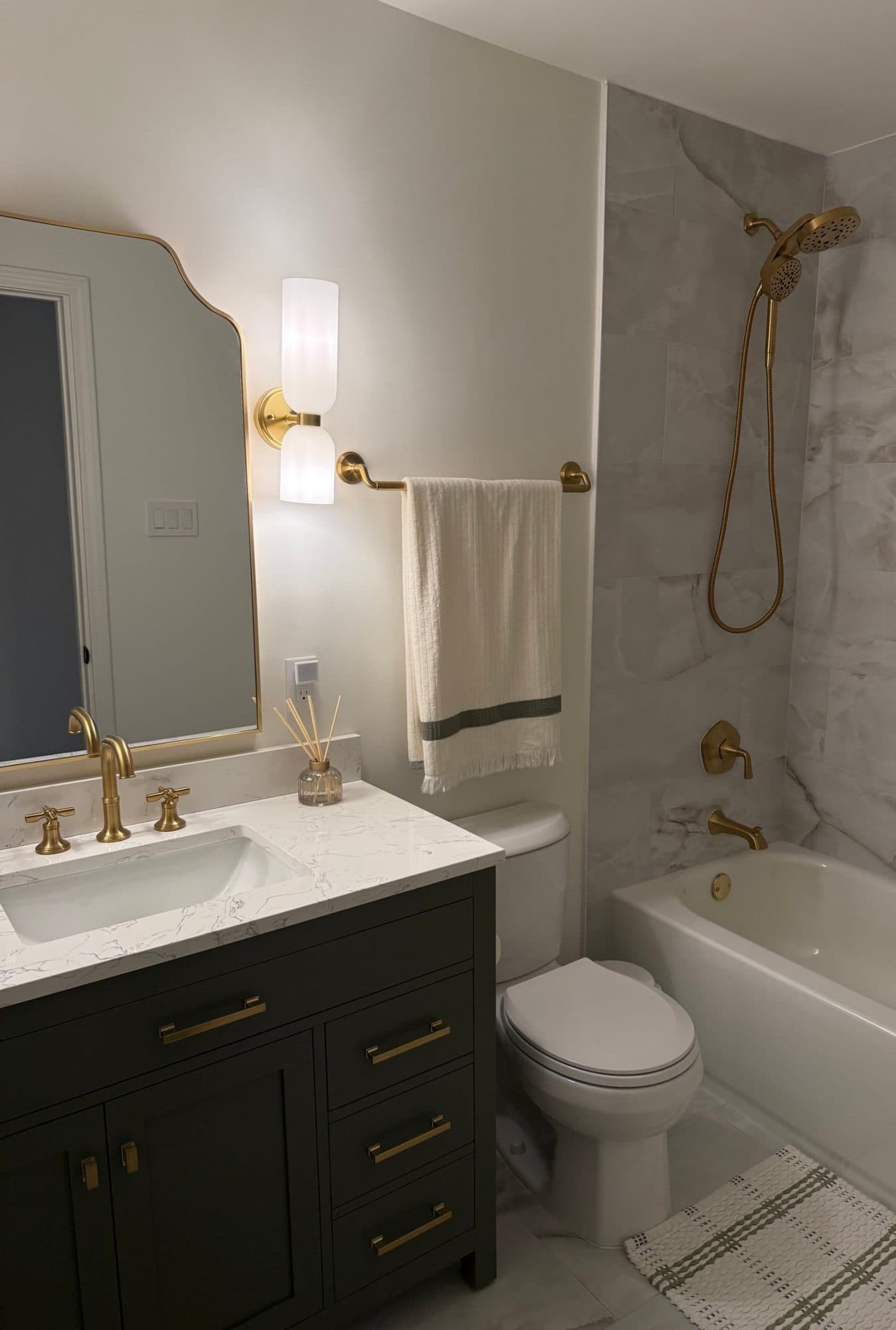 Hall bathroom remodel in SouthPark, Charlotte: charcoal shaker vanity, brass fixtures and marble-look tile tub surround