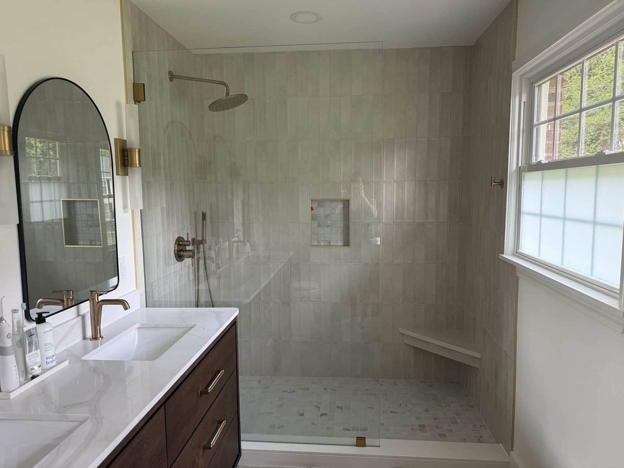 Walk-in shower with frameless glass, rain head and corner bench in a SouthPark, Charlotte primary bathroom