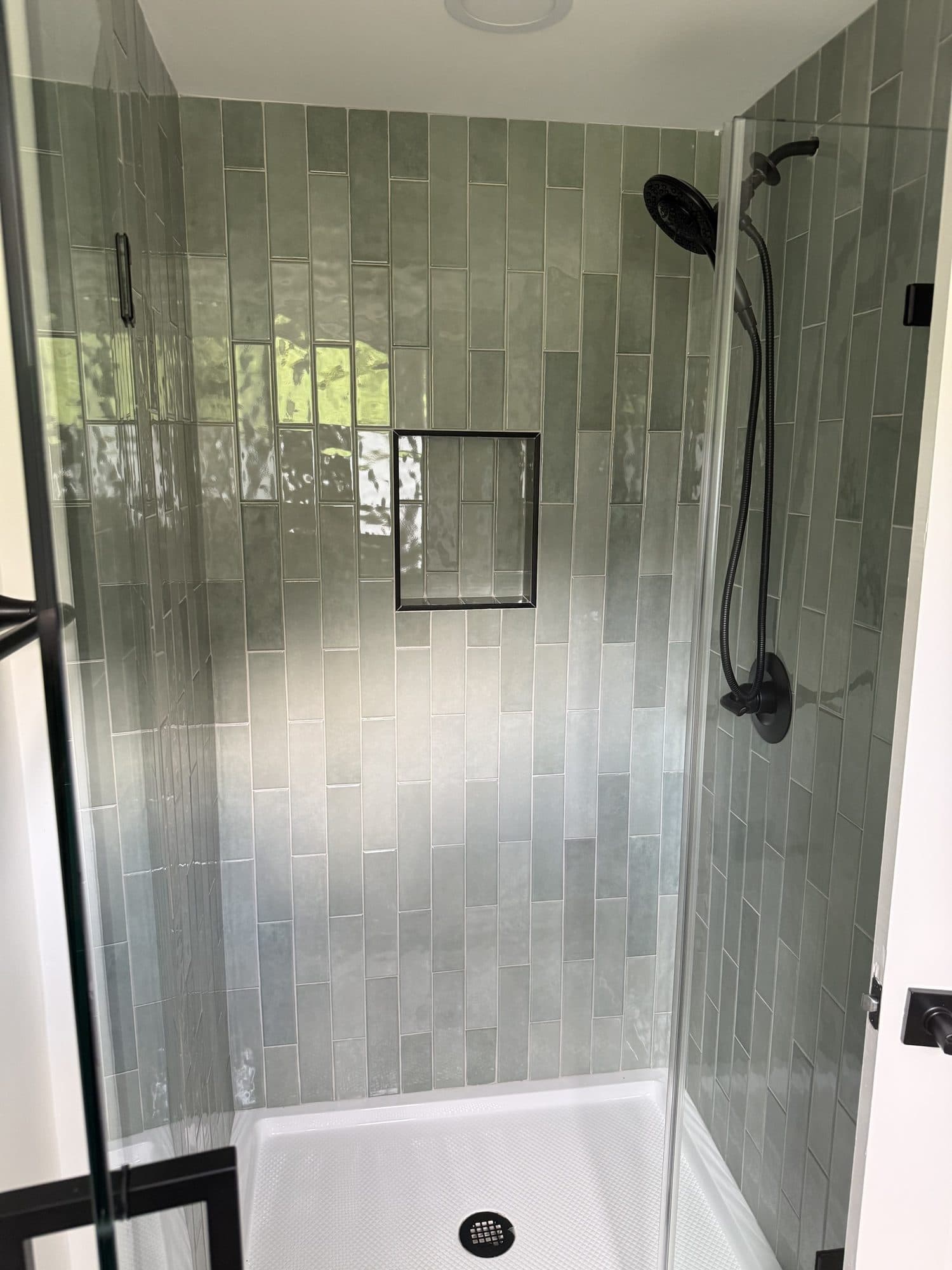 Glossy green vertical-stack tile shower with black fixtures and recessed niche in a SouthPark, Charlotte home