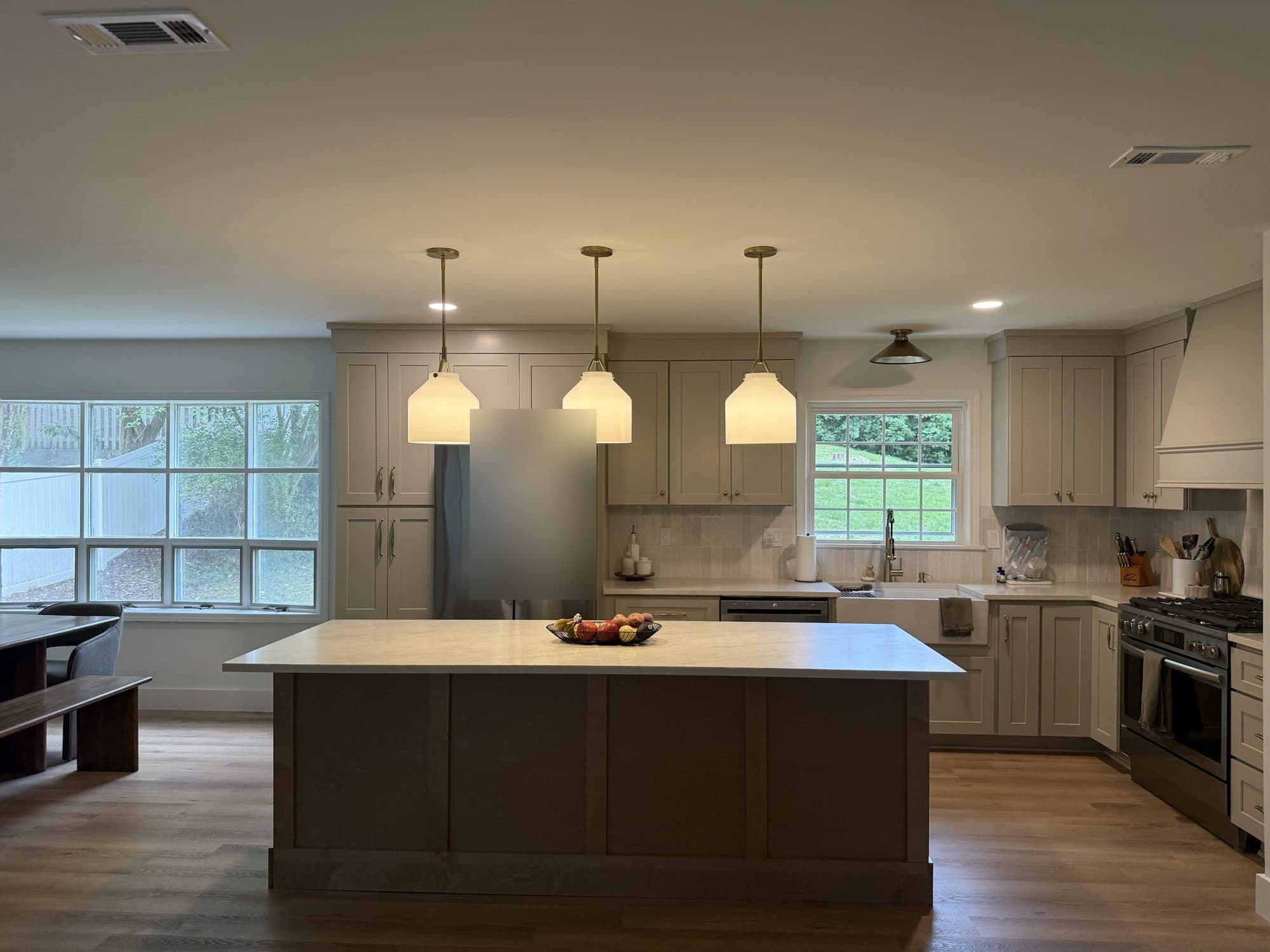 New kitchen with large stained island, three pendant lights, greige shaker cabinets and farmhouse sink in a SouthPark, Charlotte remodel