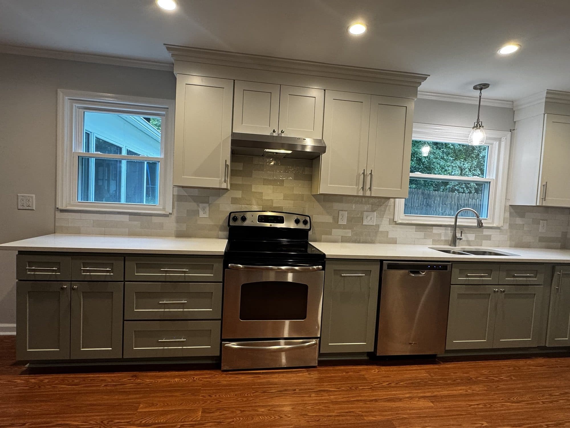 Remodeled kitchen wall in Stonehaven, Charlotte NC with new range, sink between two windows, shaker cabinets and handmade-look tile backsplash