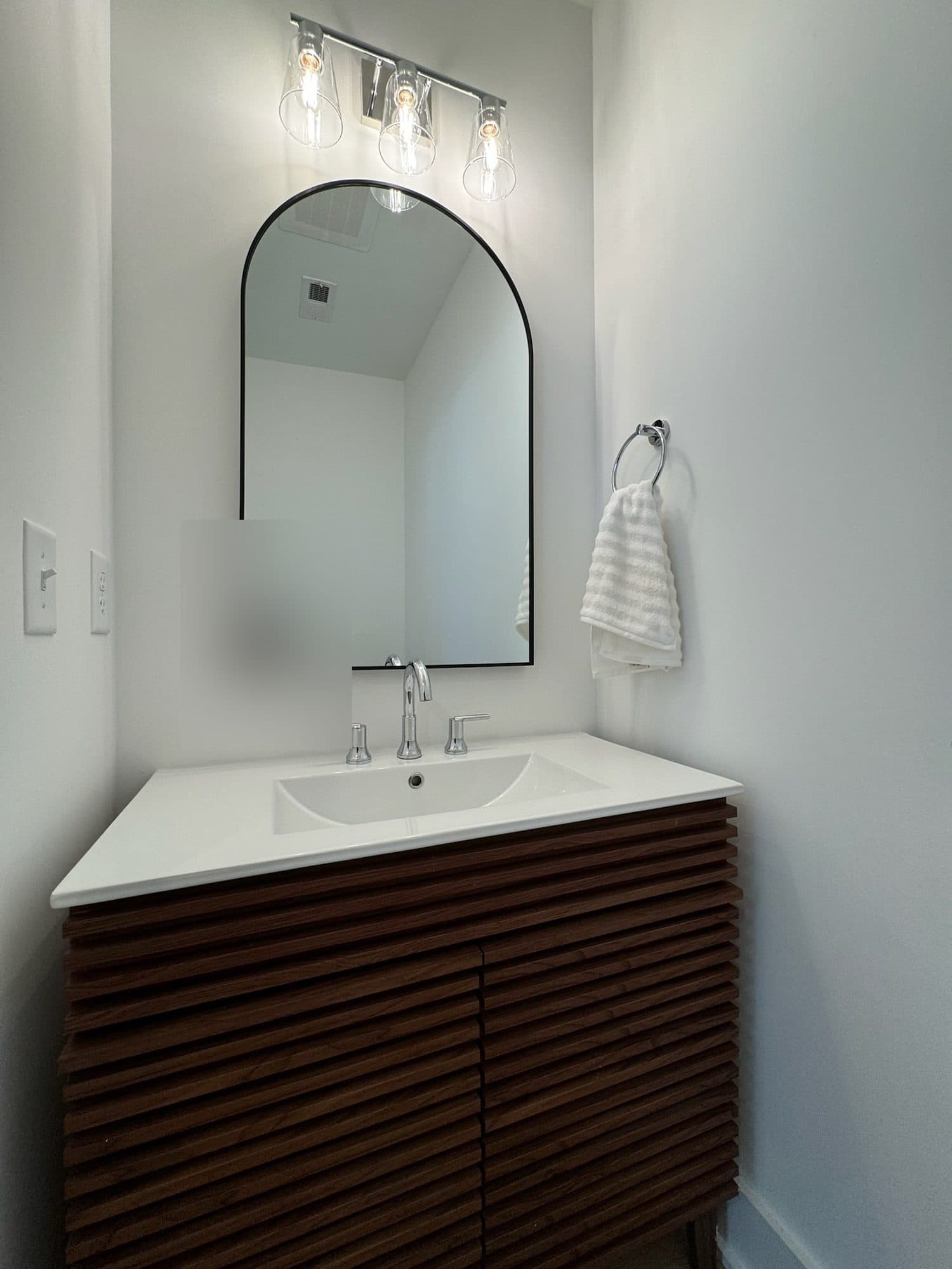 Powder room with walnut slat vanity and arched mirror at The Arches townhomes, Charlotte NC