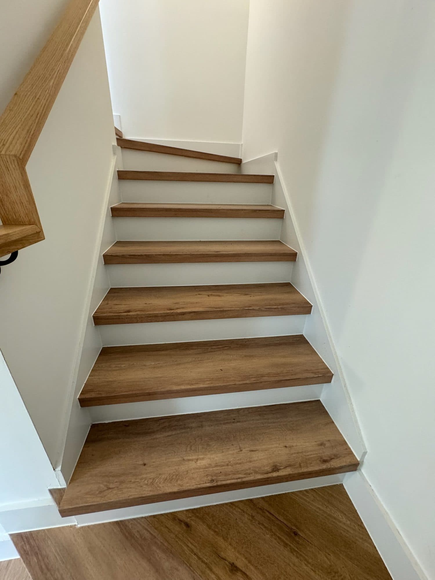 LVP stair treads with white risers and oak handrail at The Arches townhomes, Charlotte NC