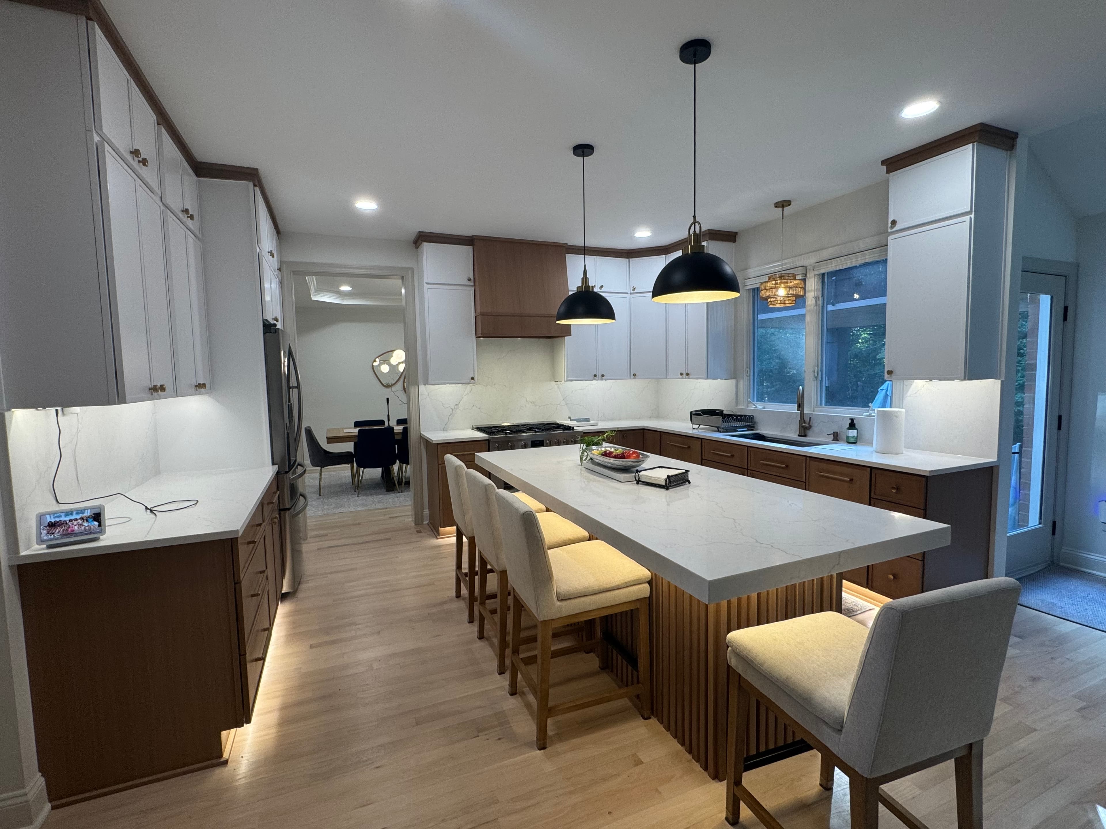 Charlotte kitchen remodel with two-tone white and warm wood cabinets, quartz waterfall island, and black pendant lights.