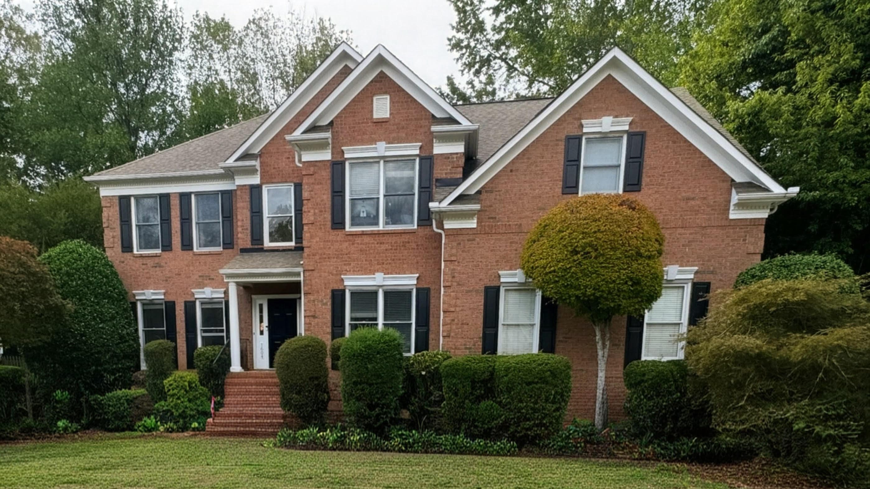 Brick colonial home exterior in Charlotte showing a clean roofline after roofing work.