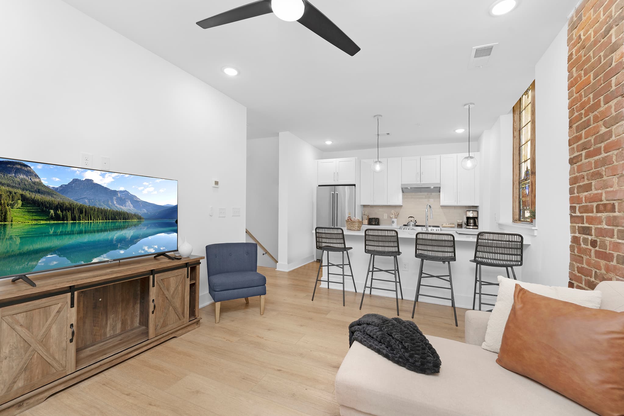 Open-plan Charlotte remodel with white painted walls, LVP flooring, and exposed brick accent.