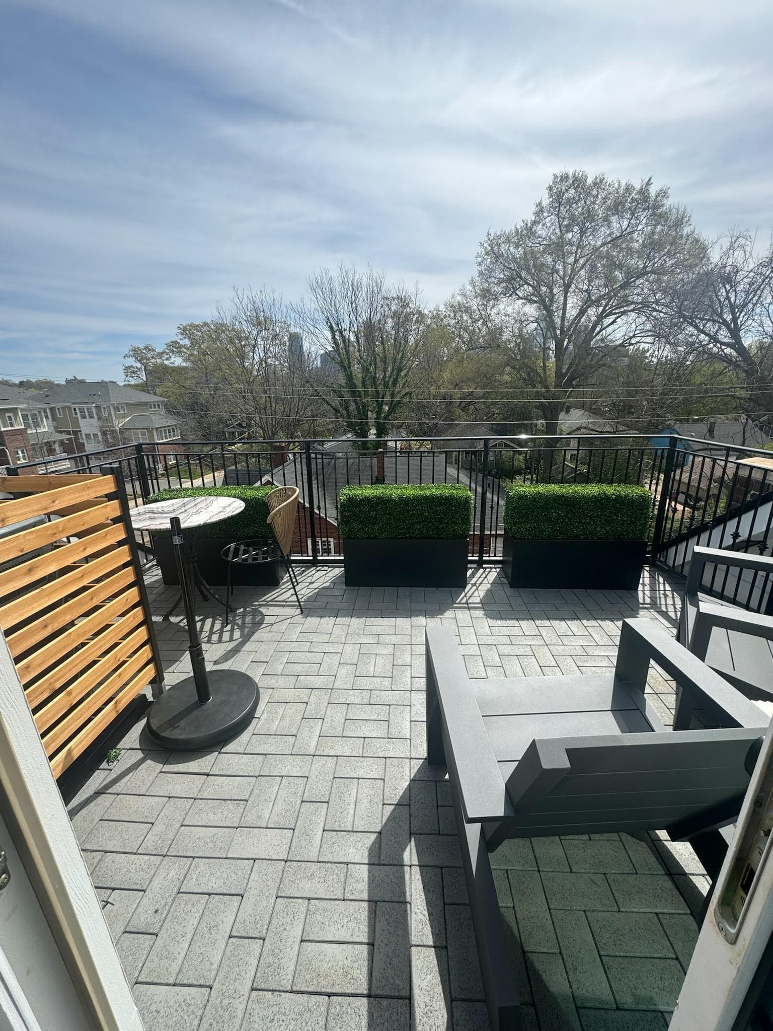 Rooftop patio project in Charlotte with stone tile, black railings, and skyline views.