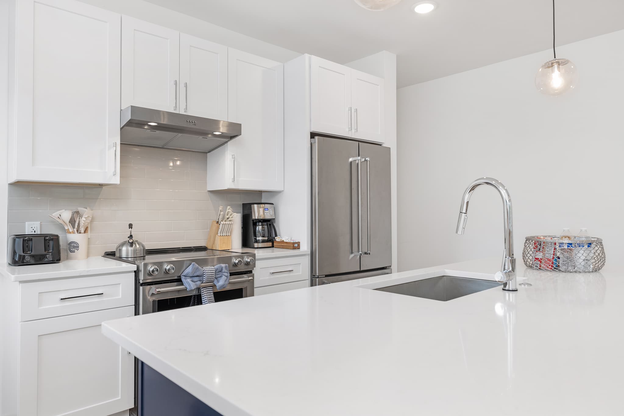 White shaker kitchen in Charlotte with subway backsplash, quartz countertops, and pendant lighting.
